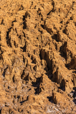 A rocky, barren landscape with many small holes and crevices. Scene is desolate and rugged, with the...