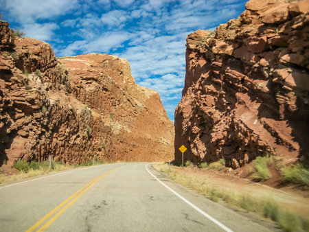 A road with a yellow sign that says "No U-turns" in the middle of a canyon.の写真素材
