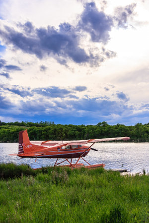 A small red plane is sitting on the water. The sky is cloudy and the water is calmの写真素材
