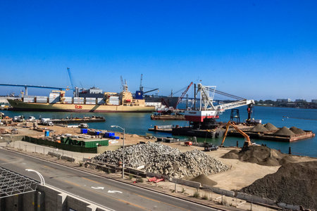 A large ship is docked at a port with a crane lifting a container. The scene is calm and peaceful, with the water and sky providing a serene backdropの写真素材