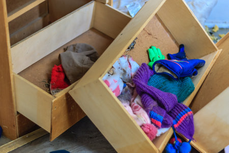 A messy drawer with a pile of clothes and a pair of gloves. The drawer is open and the clothes are scattered all over the drawerの写真素材