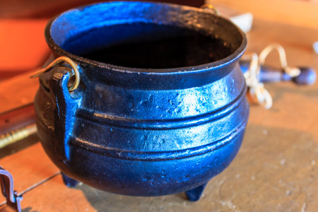 A blue pot with a handle sits on a table. The pot is old and has a rustic appearanceの写真素材