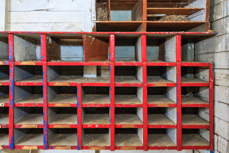 A row of red wooden shelves with blue trim. The shelves are empty. The shelves are old and worn