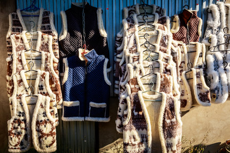 A rack of vests with a variety of colors and patterns. The vests are hanging on a metal rackの写真素材