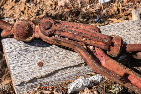 A rusty chain is laying on a wooden surface. The chain is old and worn, with rust covering most of it. The wooden surface is also old and worn, with a few cracks and splintersの写真素材