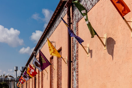 A row of flags hanging from a building. The flags are of different colors and sizes. The flags are arranged in a way that they are not touching each otherの写真素材