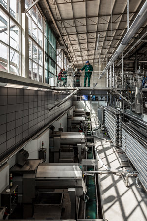 A man is standing on a platform in a factory. The factory is filled with machinery and the man is...