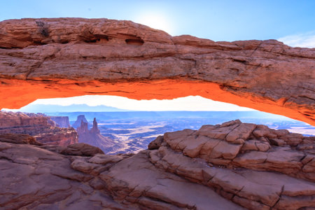 Mesa Arch spans 90 feet and stands at the edge of a mesa precipice thousands of feet above the Colorado River gorge. For a few moments at sunrise the underside of the arch glows dramatically red and orange.の写真素材