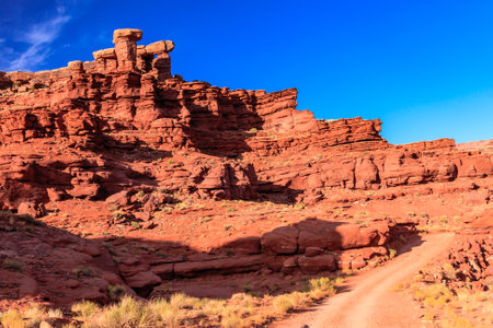 A rocky desert landscape with a road running through it. The sky is blue and the sun is shining...