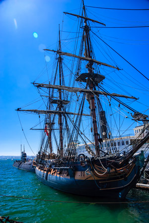 A large ship with a red flag on the mast. The ship is docked in a harborの写真素材