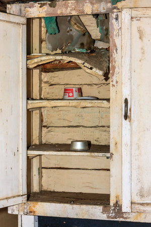 A cabinet with a shelf that has a can of food on it. The cabinet is old and has a lot of damageの写真素材