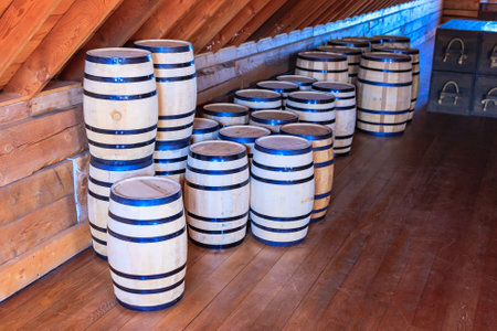 A row of barrels are stacked on top of each other. The barrels are wooden. The barrels are stacked in a way that they are all facing the same directionの写真素材