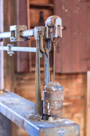 A rusty scale with a weight on it. The scale is old and has a worn appearance. The weight is hanging from the scale, and it is quite heavy. Scene is one of nostalgiaの写真素材