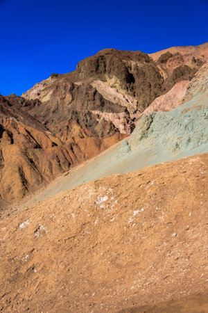 A mountain range with a blue sky in the background. The mountains are brown and green. The sky is clear and brightの写真素材