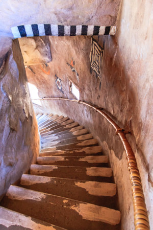 A spiral staircase with a railing and a window. The staircase is made of stone and has a rustic feelの写真素材