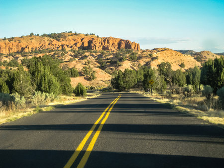 A road with a yellow line down the middle. The road is empty and the sky is blueの写真素材