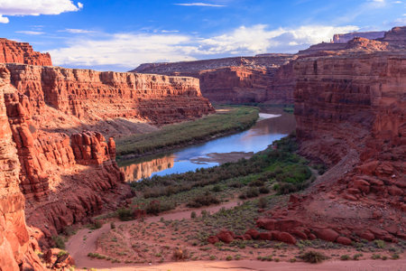 A river runs through a canyon with a beautiful blue sky in the background. The canyon is full of rocks and the river is calmの写真素材