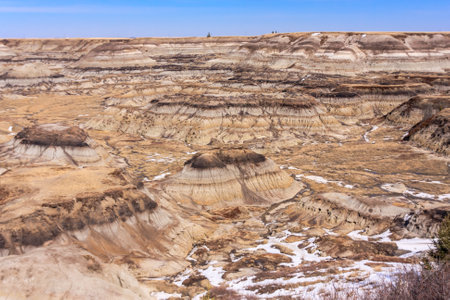 A desolate landscape with a few people in the distance. The sky is clear and the sun is shining brightlyの写真素材