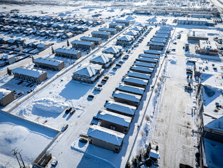 Snowy residential area with many houses and cars. The houses are all covered in snow and the cars are parked on the street. Scene is peaceful and quiet, with the snow covering everythingの写真素材
