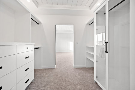 White room with a closet and a dresser. The room is empty and has a clean, minimalist lookの写真素材