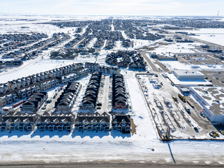 Snowy cityscape with a large number of houses and a few cars. The houses are mostly white and the snow is covering the groundの写真素材