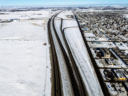 Snowy road with a city in the background. The city is small and has a lot of houses