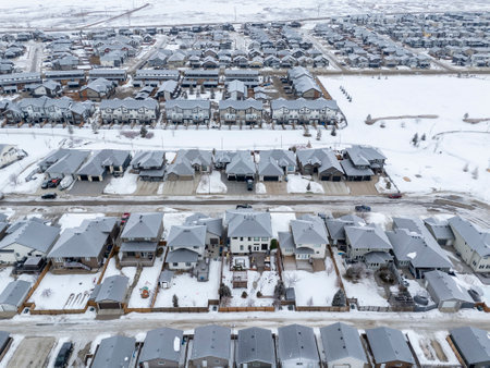 Snowy street with houses on both sides. The houses are all white and have roofs. The street is empty and quietの写真素材
