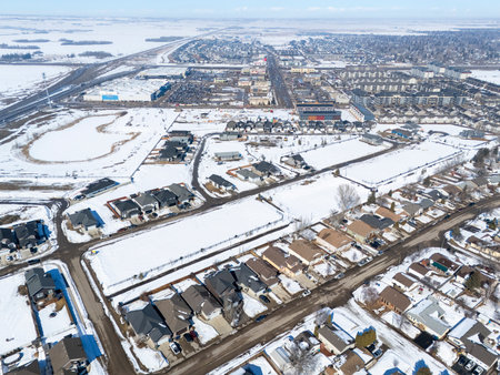 Snowy cityscape with houses and a street. The houses are mostly white and the street is covered in snowの写真素材