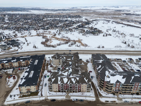 Snowy cityscape with a large apartment complex in the foreground. The sky is overcast and the snow is fallingの写真素材