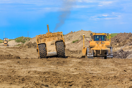 Caterpillar bulldozer is in the middle of a construction site. The bulldozer is surrounded by other...