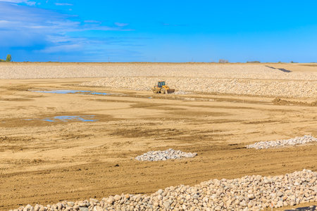 A vehicle is driving through a field of rocks. The field is dry and barren, with no vegetation in...