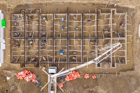 Construction site with a crane and a pile of orange bags. The crane is lifting a large object