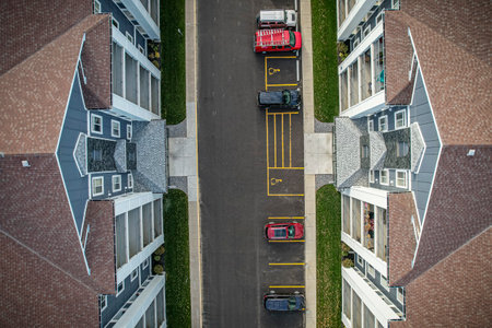 Street view of a residential area with a row of parked cars. The cars are parked in a row, with some...