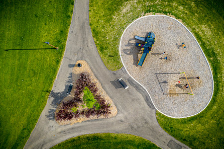 Park with a playground and a triangular flower bed. The park is green and has a peaceful atmosphereの写真素材