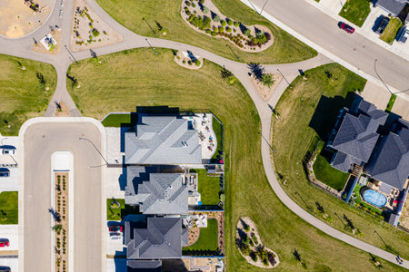 Residential neighborhood with houses and a pool. The houses are all different sizes and styles, and the pool is located in the middle of the neighborhood. The street is lined with treesの写真素材