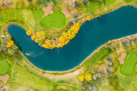 Golf course with a blue waterway running through it. The waterway is surrounded by trees and grassの写真素材
