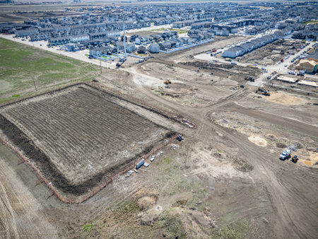 Dirt field with a large hole in the middle. The field is surrounded by a fence. The area is in the...