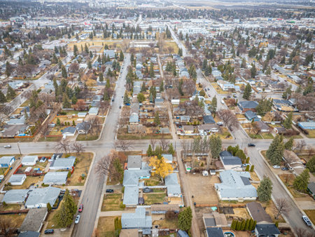 City street view with houses and cars. The houses are mostly white and the cars are parked on the streetの写真素材