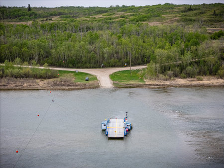 Small ferry is floating on a lake near a dock. The water is calm and the sky is cloudyの写真素材