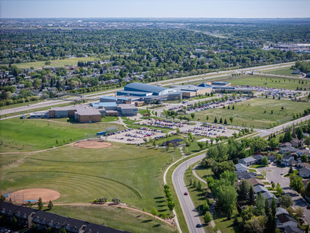 Large field with a baseball diamond and a few houses in the background. The houses are all lined up along the roadの写真素材