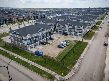 Residential area with many houses and a few cars parked in a lot. The houses are mostly brick and the lot is surrounded by a fenceの写真素材