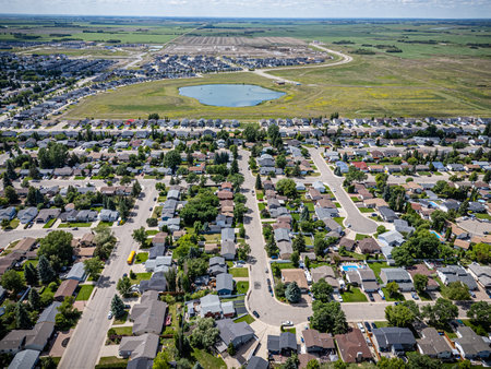 Residential neighborhood with houses and a lake in the background. The houses are spread out and there are several cars parked on the streetsの写真素材