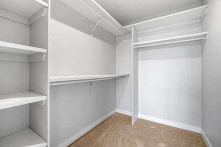 White closet with shelves and a hanging rod. The closet is empty and the walls are whiteの写真素材