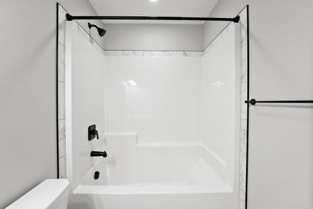 Bathroom with a white shower and tub, and a black towel rack. The shower curtain is black and the...