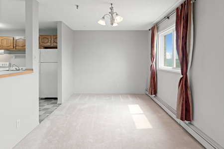 Large, empty living room with a window and a fireplace. The room is clean and uncluttered, with a...
