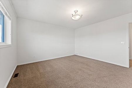 Large empty room with a white ceiling and white walls. The room is bare and has no furnitureの写真素材
