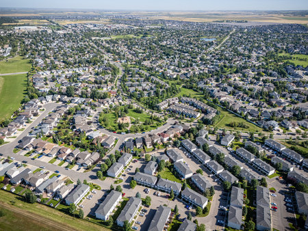 High-resolution aerial drone view of Arbor Creek, a residential neighborhood in northeast Saskatoon, Saskatchewan. The image showcases rows of family homes, winding streets, and green spaces surrounded by natural prairie landscape. Perfect for use in real estate marketing, urban planning visuals, travel guides, or editorial projects highlighting Saskatoonâs suburban communities.の写真素材