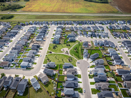 Drone aerial of South Kensington, a new and developing residential area on Saskatoonâs west side. The image highlights modern homes, storm ponds, commercial zones, and community green spaces within a growing suburban landscape. Perfect for real estate marketing, editorial features, or urban planning visuals showcasing Saskatoonâs expanding neighbourhoods.の写真素材