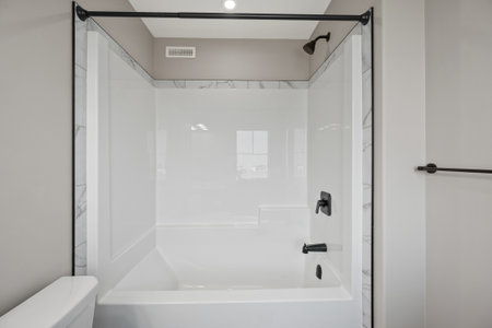White bathtub with a black trim. The bathtub is empty. The bathroom is clean and well-maintained