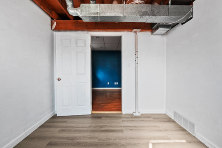 White door with a knob is open in a room. The door is in front of a blue wallの写真素材